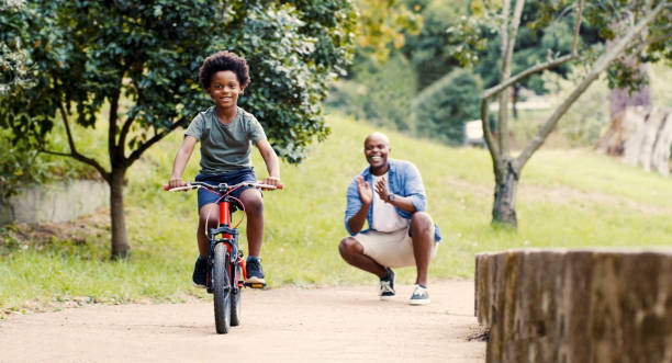 istock Nature, child on bicycle and proud dad teaching kid to ride on path in park, child development and growth. Garden, trust and support from black man for boy riding bike, safety and security in family. 1439733281