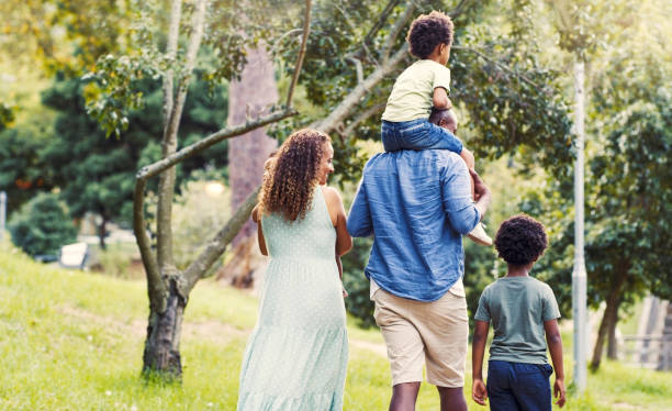 jardín, paseo y familia en un picnic al aire libre en la naturaleza durante una aventura de vacaciones de verano. feliz madre, padre y niños caminando afuera en un parque en un viaje de vacaciones para divertirse en méxico. - family grass toddler african descent fotografías e imágenes de stock