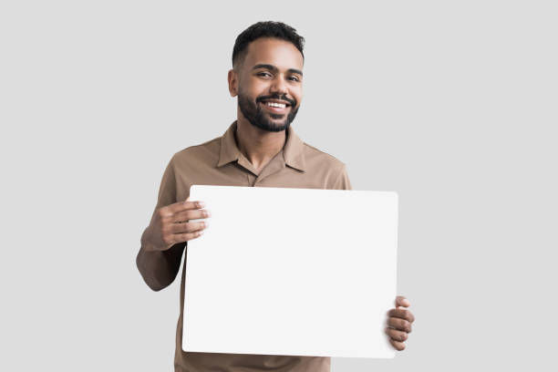 uomo sorridente felice che mostra il banner bianco vuoto - holding a sign foto e immagini stock