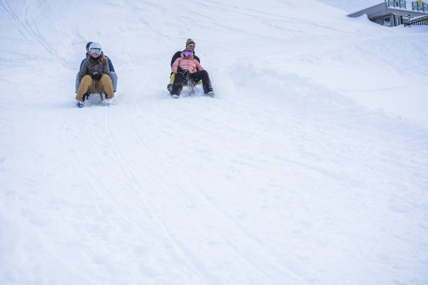 verrückte glückliche freunde, die spaß beim rodeln auf schneehohen bergen haben - switzerland hotel skiing people stock-fotos und bilder