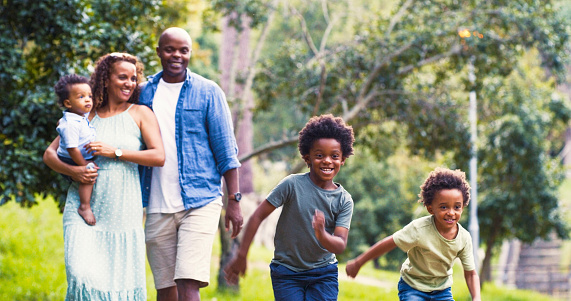 Park, running and happy family with children in a park, fun and summer holiday or vacation in Brazil. Black mother and father walking with kids in playful race with energy, love or happiness outdoor