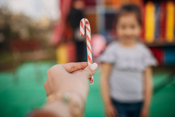 Close-up of preschool girl with bag with candy bonbons and lollipop. Different sweets in a bag. No face
