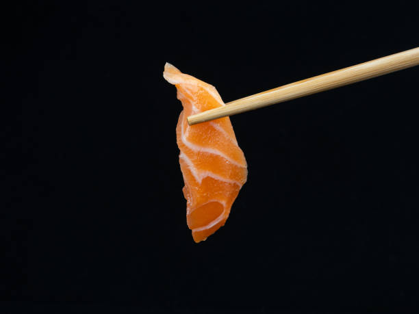 istock Chopsticks hold salmon sashimi on black background 1439741686