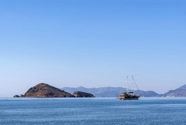 A sailing tour boat at sea in Fethiye, Turkey and a small rocky island in the background.