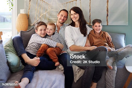 istock A family with three young boys is sitting on the sofa in their living room 1439750755
