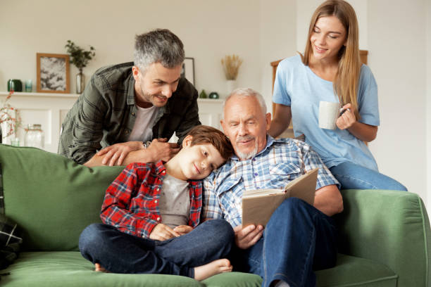 mehrgenerationen-glückliches familienlesebuch. bildungskonzept - grandparent family reading inside of stock-fotos und bilder
