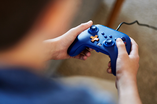 a closeup of a blue controller in the hands of a boy