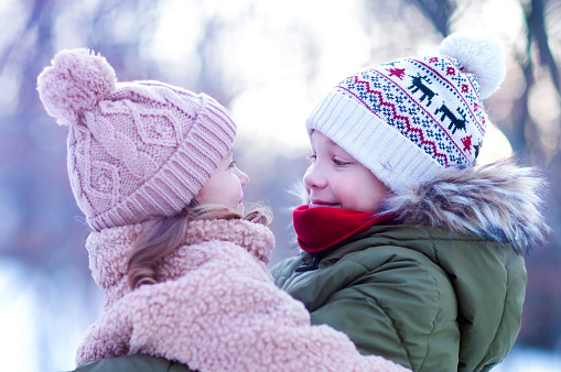the older brother hugged his little sister, looking at her tenderly and smiling. winter