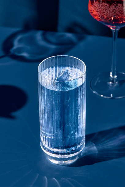 istock Transparent cocktail with gin and tonic on blue background with shadow. Gin tonic cocktail on coloured background in trendy style. Contemporary concept with alcohol beverage. Bartender cocktail. 1439755903