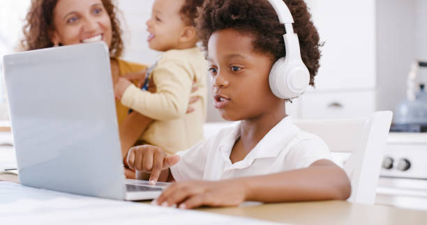 istock Education, learning and child on laptop at table distance learning and online lesson in home. Family, boy and virtual learning by boy in interactive e learning class, homeschool and happy in kitchen 1439756231