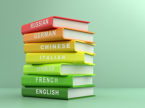 Multicolored foreign language books in front of a green background. Learning new languages and translation concept