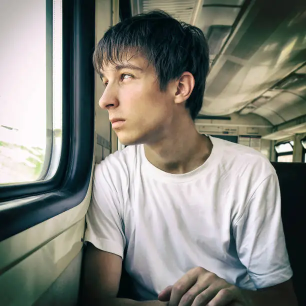 Toned Photo of Sad Young Man sit in the Train by the Window