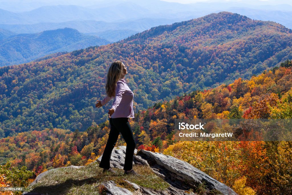 Free woman enjoying nature in the mountains. Happy woman with arms raised relaxing on autumn hiking trip. Smiling woman on top of the mountain enjoying beautiful fall scenery. Blue Ridge Mountains, near Asheville, North Carolina, USA Arms Outstretched Stock Photo