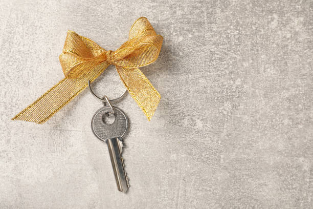 istock Key with golden bow on light grey stone background, top view and space for text. Housewarming party 1439764168