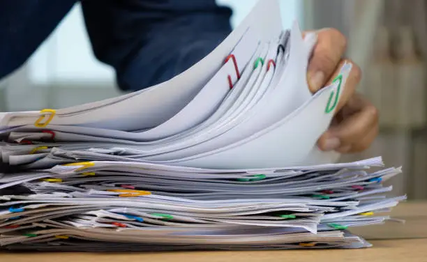 Photo of Hand holding of Stack of Group report papers Document clipped in color clips, business, and education concept.