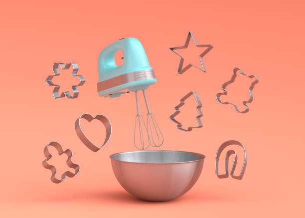 Metal bowl with electric mixer and cookie cutters on coral background stock photo