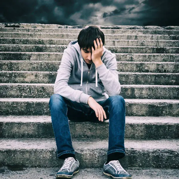 Toned Photo of Sad Young Man sit on the Stairs