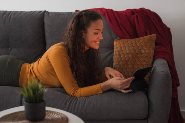 istock Happy girl resting on a sofa and using digital tablet 1439768649
