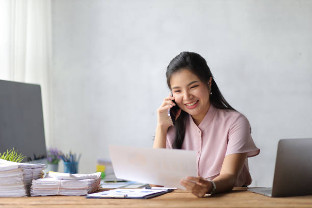 istock Happy business woman in office talking on the phone and analyzing work schedule. 1439768852