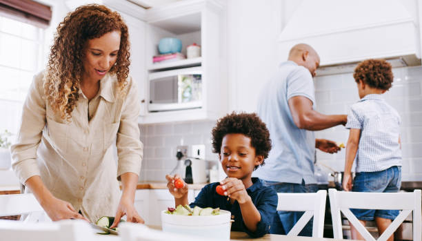 cucina, cucina e genitori neri della famiglia con bambini preparano ingredienti alimentari, forniture o materiali di consumo per cena, pranzo o brunch. macedonia di frutta, salute del benessere e nutrizionista mamma aiuta a fare pasto - looking at camera full length outdoors image technique foto e immagini stock