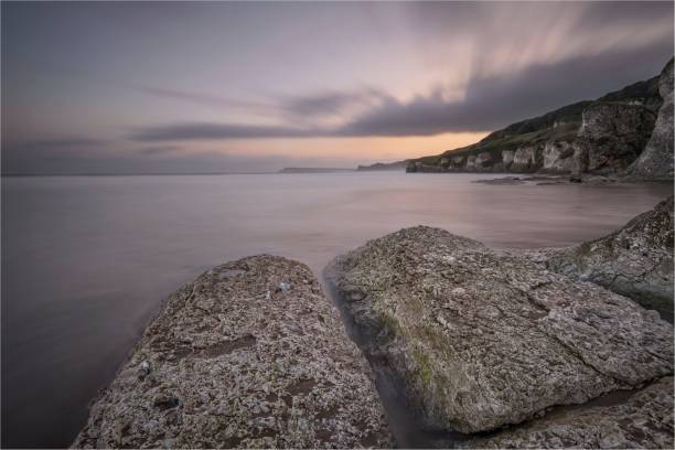 vue imprenable sur les formations rocheuses sur le rivage contre le ciel du coucher du soleil, longue exposition - long exposure rock cloud sky photos et images de collection