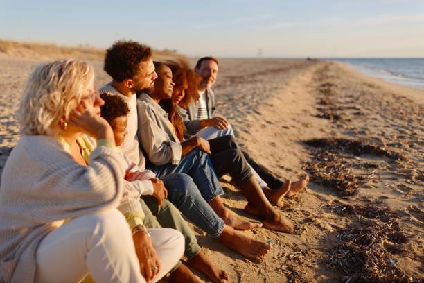 multi-generation family enjoying cold sunny day at he beach - senior adult winter senior women daughter imagens e fotografias de stock