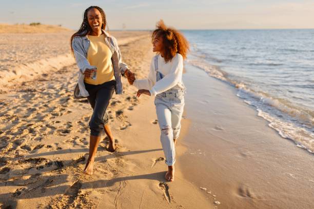 istock Mother and daughter running along the beach 1439770972