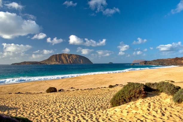 istock Idyllic sandy beach with mountains and a cloudy sky in the background 1439771294