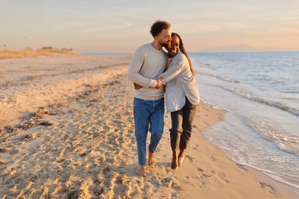 istock Couple walking at beach during sunset 1439771590