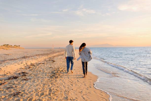 istock Couple walking at beach during sunset 1439771785