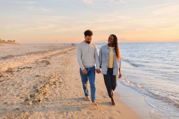 istock Couple walking at beach during sunset 1439771950