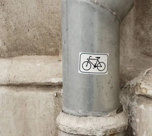 A vertical shot of a white bicycle symbol sticker on a downspout pipe