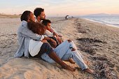 istock Happy multiracial parents enjoying sunset with their children at beach 1439773160