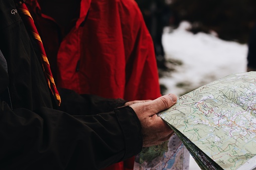 A closeup shot of two people holding and reading a map in a snowy area