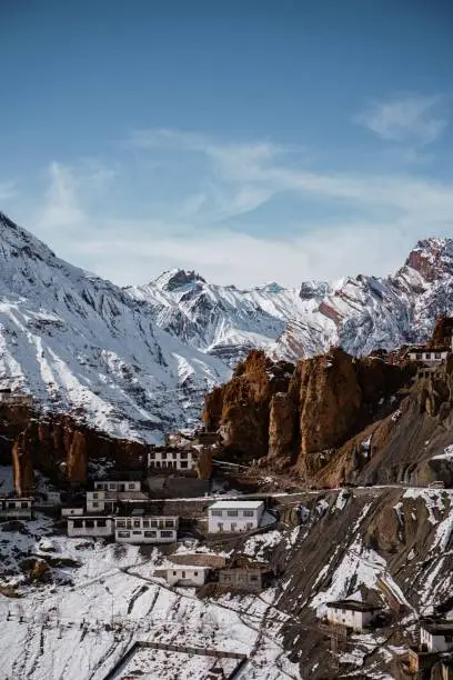 A vertical shot of a Dhankar monastery in Spiti Valley with snow-covered mountains in the background
