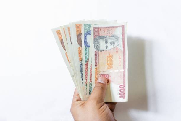 istock Hand holding cash Cuban pesos isolated on a white background 1439773693