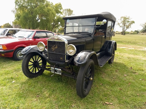 Chascomus, Argentina – April 10, 2022: Old black Ford Model T Fordor Phaeton 1926 in the countryside. Nature green grass and trees. Classic car show. Copyspace
