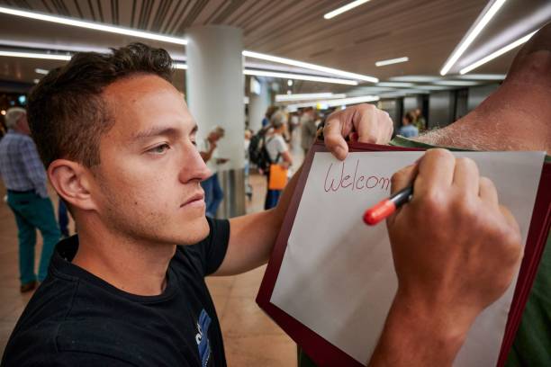 istock Young Hispanic man writing an airport welcome greeting 1439774700