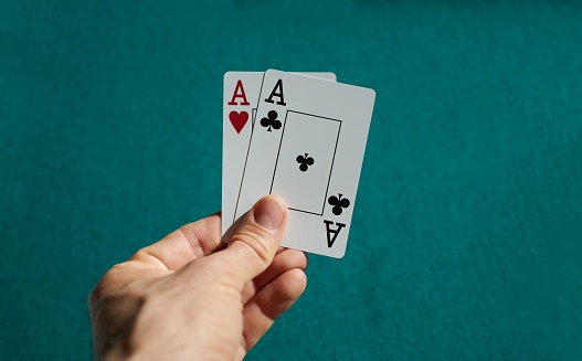 The player points to the winning combination of one pair in a poker game on a green table with chips and in a club.
