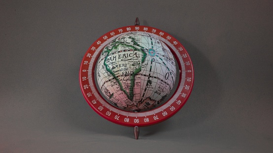 A closeup shot of a small globe behind a grey background