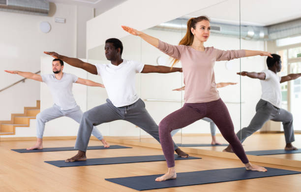 istock Girl practicing Virabhadrasana during group yoga training 1439775412