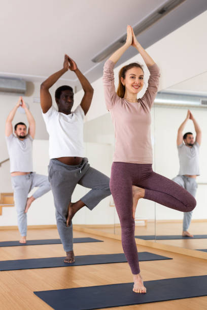 istock Group of people practising tree pose in gym 1439775422