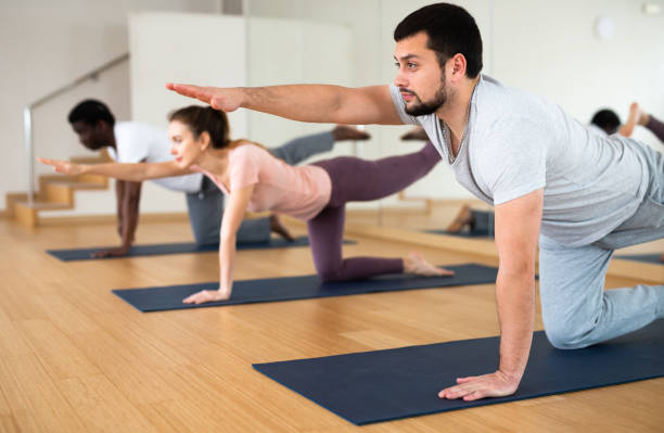 istock Man doing bird dog exercise with other people in gym 1439775517