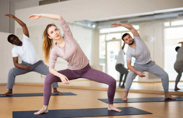 istock Woman performing stretching during group yoga training 1439775527