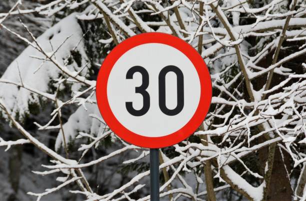 istock Tree branches covered with snow and a speed limit sign  on the foreground 1439775616