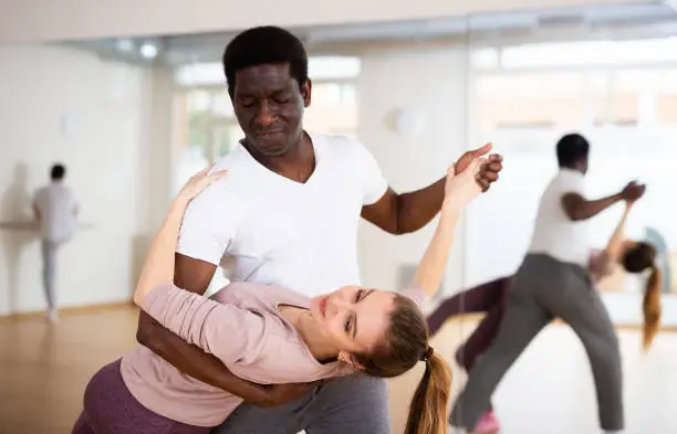 African-american man and european woman practicing salsa moves in dancing room.