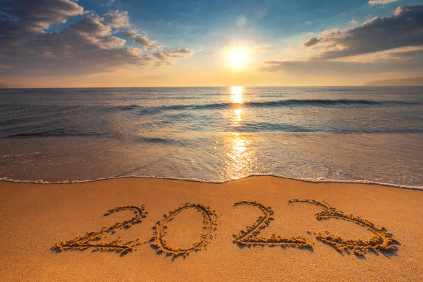Happy New Year 2023 concept, lettering on the beach. Written text on the sea beach at sunrise. stock photo