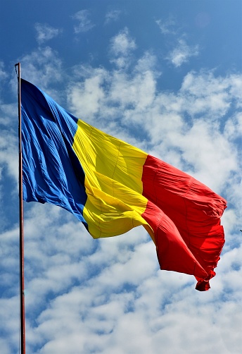 The three-colored Romanian flag against the blue sky