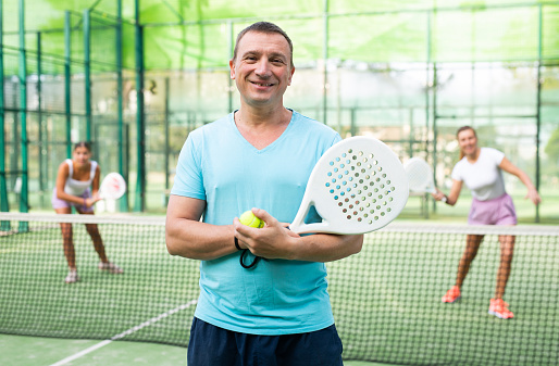Portrait of cheerful man padel tennis player in outdoor court.