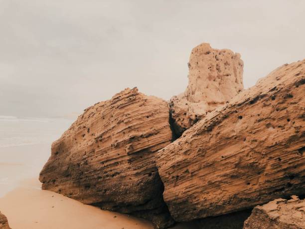 Rocky cliffs on a beach over a background of a cloudy sky